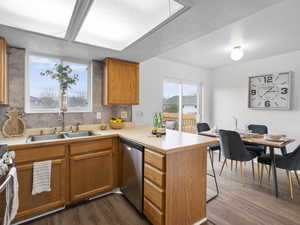 Kitchen featuring light countertops, a peninsula, dark wood-style flooring, stainless steel appliances, and brown cabinets
