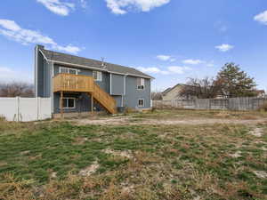Back of property featuring a fenced backyard, stairway, and a deck