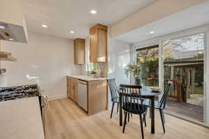 Kitchen with ventilation hood, light wood finished floors, recessed lighting, dishwashing machine, and gas stove