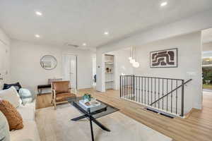 Living room featuring recessed lighting, light wood-style flooring, attic access, and built in shelves