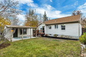 Back of property with a lawn, a patio, brick siding, and a shingled roof