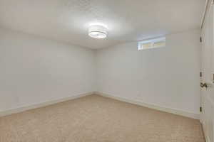 Unfurnished room with a textured ceiling and light colored carpet