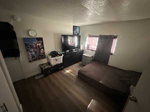 Bedroom featuring a textured ceiling and dark wood finished floors