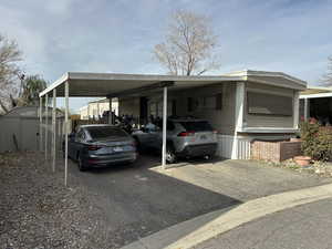 View of parking with a carport, driveway, and a storage shed