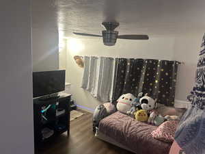 Living room with a textured ceiling, dark wood-style floors, and ceiling fan