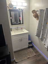Half bath with dark wood-type flooring and vanity