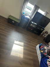 Bedroom with dark wood-style floors and refrigerator