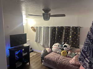 Bedroom with a textured ceiling, dark wood-style flooring, and ceiling fan