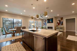 Kitchen with open floor plan, dark brown cabinetry, dishwasher, a fireplace, and recessed lighting