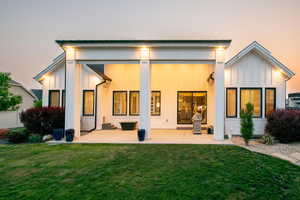 Rear view of property featuring a patio, a lawn, and board and batten siding