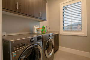 Washroom with cabinet space, washing machine and dryer, and light tile patterned floors