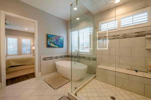 Full bathroom with a freestanding bath, light tile patterned flooring, ensuite bathroom, tile walls, and recessed lighting
