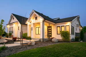 Modern farmhouse with board and batten siding, a porch, a front yard, and a shingled roof