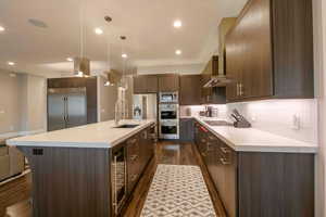Kitchen featuring modern cabinets, dark wood-style floors, built in appliances, dark brown cabinets, and recessed lighting