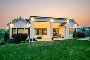 Back of property at dusk with a patio and board and batten siding