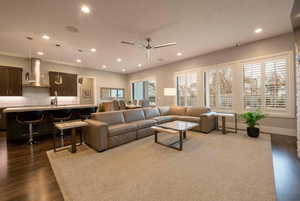 Living area with dark wood-style floors, plenty of natural light, ceiling fan, and recessed lighting
