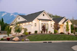 Modern farmhouse with a standing seam roof, a front yard, and roof with shingles