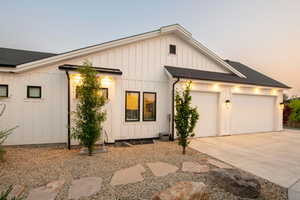 Modern farmhouse style home with board and batten siding, a shingled roof, and concrete driveway