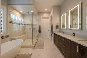 Full bathroom with light tile patterned flooring, a soaking tub, double vanity, a shower stall, and recessed lighting