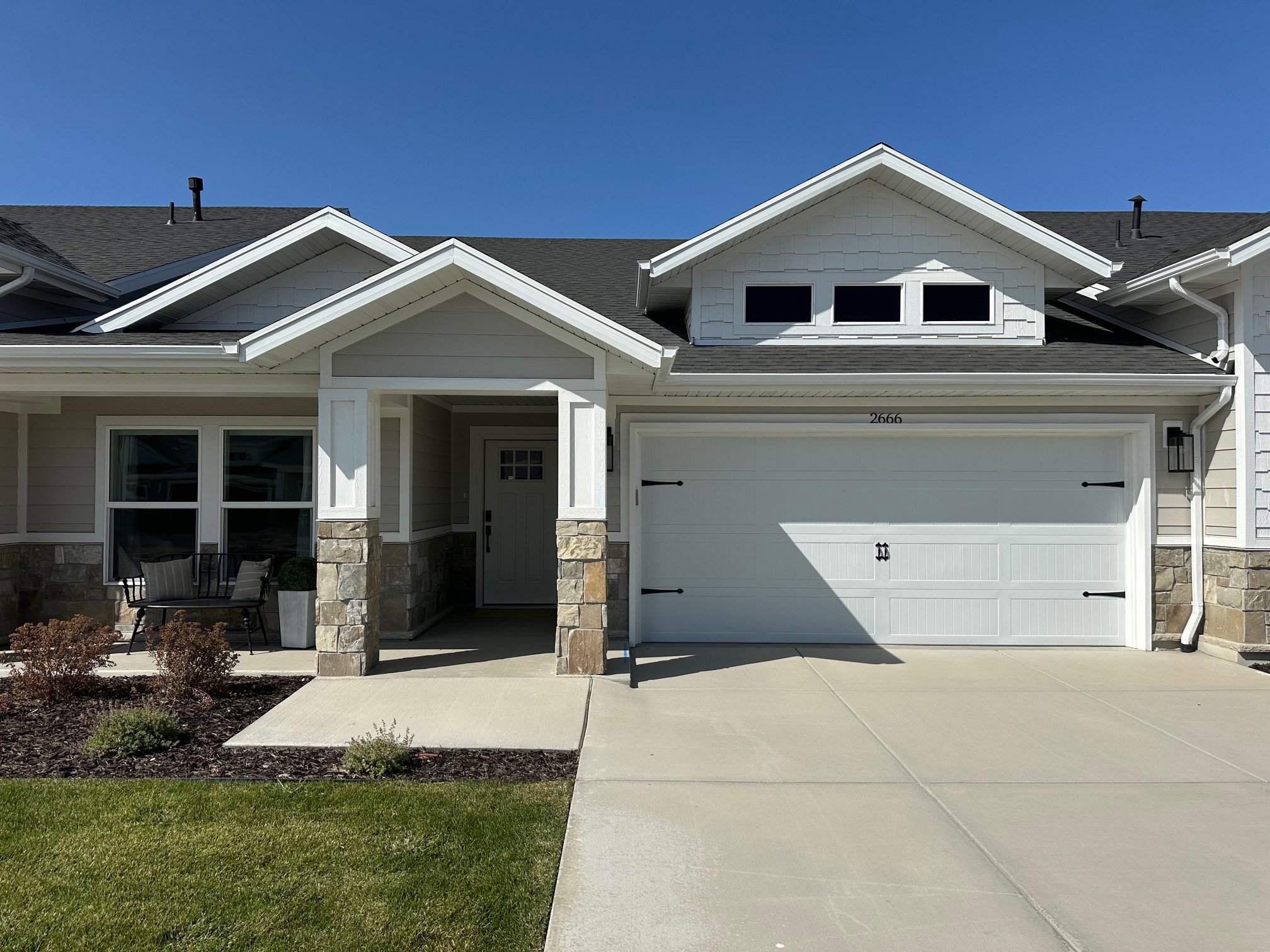 Craftsman-style home featuring stone siding, roof with shingles, concrete driveway, covered porch, and a garage