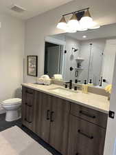Full bathroom featuring vanity, a stall shower, and dark tile patterned flooring