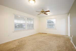 Spare room featuring light colored carpet, a textured ceiling, and a ceiling fan