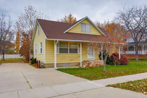 View of front facade with a shingled roof, crawl space, and covered porch
