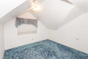 Bonus room with vaulted ceiling, carpet flooring, and a textured ceiling
