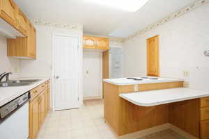 Kitchen featuring light floors, light countertops, dishwasher, and a peninsula