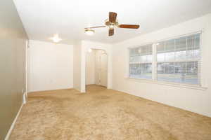 Empty room featuring light carpet, a textured ceiling, ceiling fan, and arched walkways