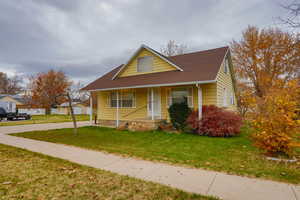 View of front of house featuring a porch, roof with shingles, and a front lawn