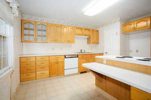 Kitchen with light countertops, white appliances, light flooring, and glass insert cabinets