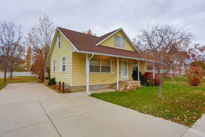 View of front of house with a front lawn, roof with shingles, covered porch, and concrete driveway