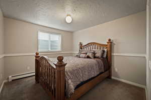 Bedroom featuring a baseboard radiator, dark carpet, and a textured ceiling