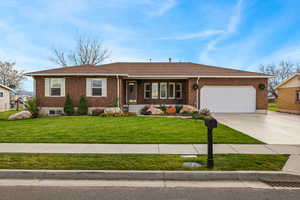 Ranch-style home featuring a porch, concrete driveway, a front yard, and brick siding