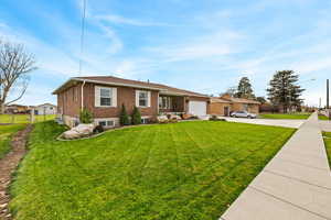 View of front of house featuring concrete driveway, a front yard, brick siding, and a garage
