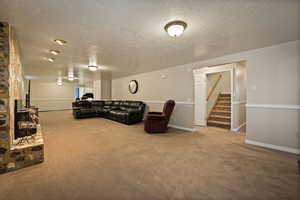 Family room with carpet flooring, stairs, and a textured ceiling