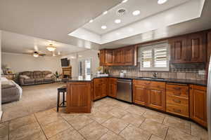 Kitchen featuring a kitchen bar, a peninsula, brown cabinets, a tray ceiling, and recessed lighting