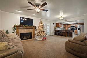Family Room with crown molding, a textured ceiling, light carpet, a tile fireplace, and ceiling fan