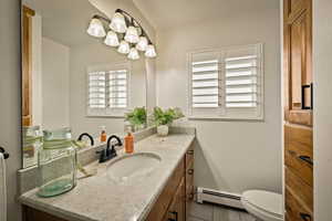 Bathroom with vanity, plenty of natural light, a baseboard heating unit, and dark tile patterned floors