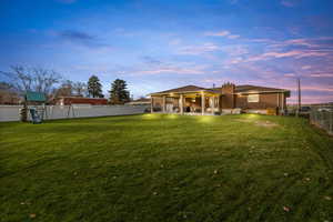 Back of property featuring a fenced backyard, a patio area, a chimney, a playground, and brick siding