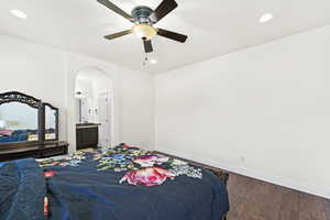 Bedroom with recessed lighting, wood finished floors, connected bathroom, ceiling fan, and arched walkways