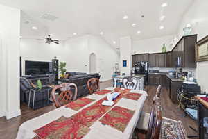 Dining room featuring arched walkways, dark wood-style flooring, high vaulted ceiling, recessed lighting, and a ceiling fan