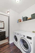 Laundry area featuring dark wood-type flooring, washing machine and clothes dryer, and a textured ceiling