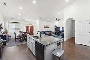 Kitchen with arched walkways, white cabinets, light stone countertops, recessed lighting, and open floor plan
