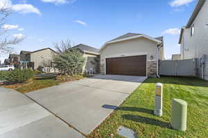 View of front of house featuring stucco siding, driveway, a gate, an attached garage, and stone siding