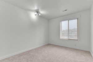 Spare room featuring light colored carpet and baseboards
