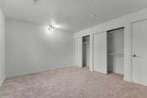 Unfurnished bedroom with multiple closets and light carpet