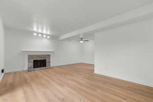 Unfurnished living room with ceiling fan, a fireplace, and light wood-style flooring