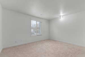 Unfurnished room featuring light carpet and baseboards